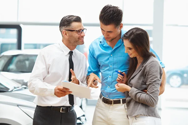 Car Salesman Invites Customers at Showroom. — Stock Photo, Image