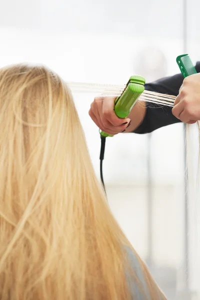 Hairdresser curling hair with straightener — Stock Photo, Image