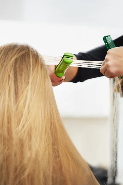 Hairdresser curling hair with straightener — Stock Photo, Image