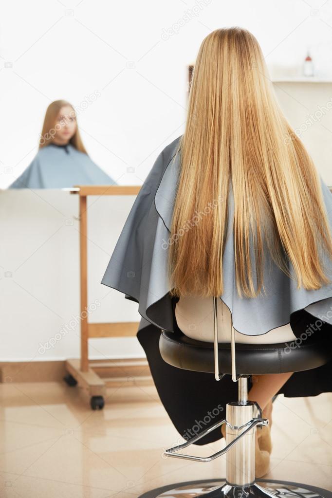 Woman in hair salon looking at mirror