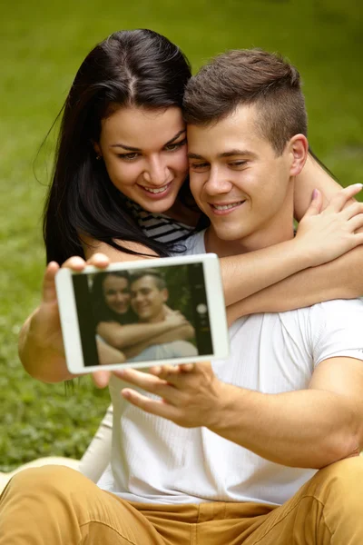 Para przy użyciu cyfrowego tabletu i uśmiechając się siedząc w pobliżu E — Zdjęcie stockowe