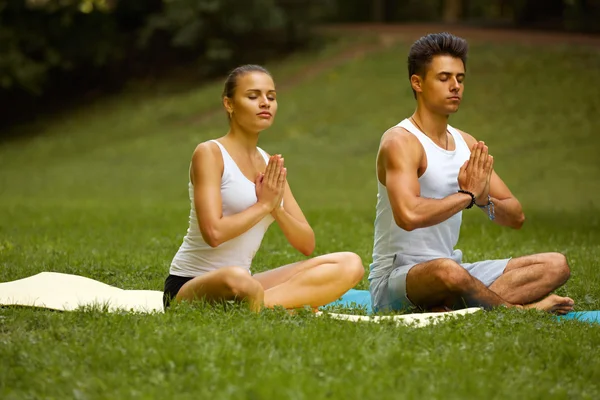 Exercício de Yoga. Jovem casal meditando no Parque de Verão — Fotografia de Stock