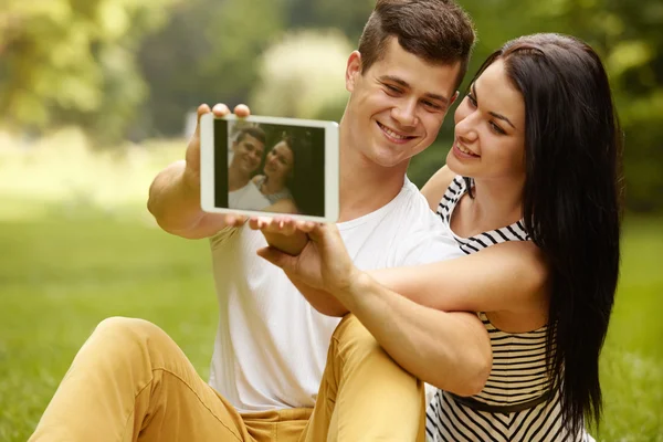 Casal usando tablet digital e sorrindo enquanto sentado perto de E — Fotografia de Stock