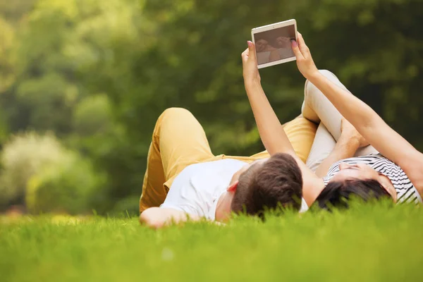 Par med elektroniska tablett i sommaren park — Stockfoto