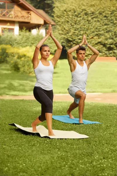Exercício de Yoga. Jovem casal meditando no clube de fitness — Fotografia de Stock