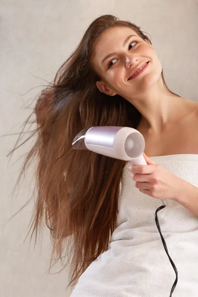 Молодая женщина дуть сушки волос в ванной комнате — стоковое фото