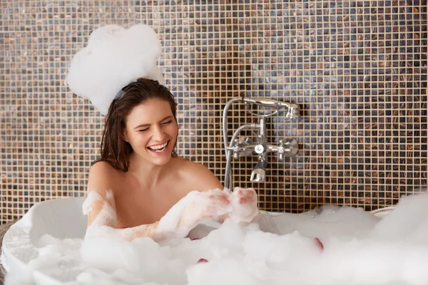 Belle femme joue avec des bulles dans le bain. Soins du corps — Photo