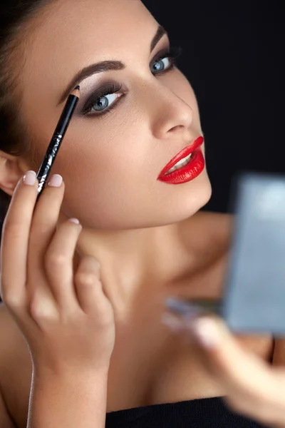 Trucco. Bella donna che fa trucco. Matita sopracciglio. Labbra rosse — Foto Stock