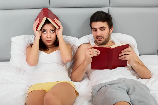Boldog házaspár ült az ágyban, olvasás otthon hálószoba — Stock Fotó