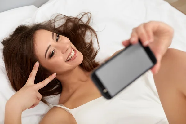 Mulher bonita tomando selfie na cama — Fotografia de Stock