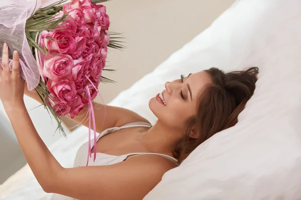 Woman Smelling a Flowers While Lying on Her Bed