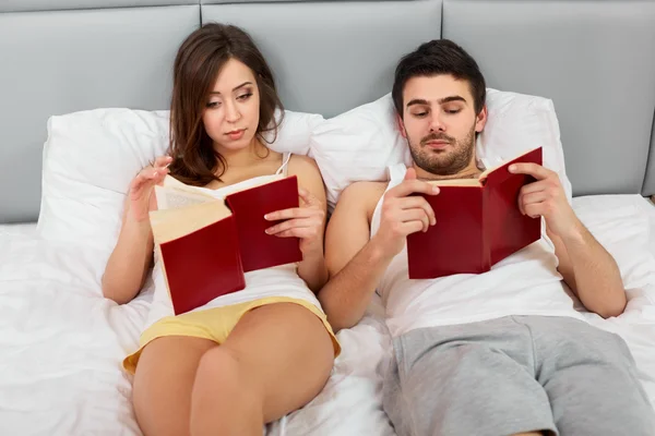 Boldog házaspár ült az ágyban, olvasás otthon hálószoba — Stock Fotó