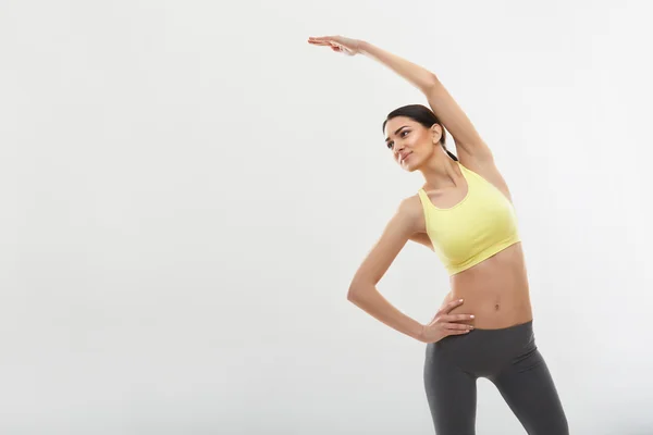 Женщина делает упражнения на растяжку против белого — стоковое фото