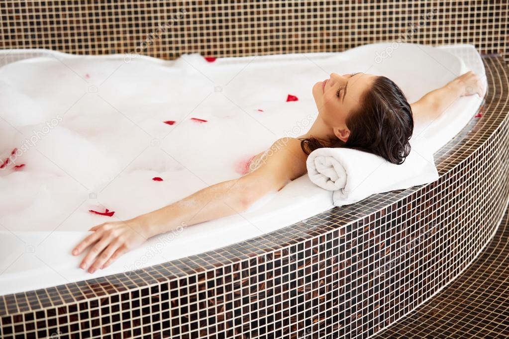 Woman Relaxing in Bubble Bath With Rose Petals. Body Care