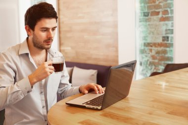 Genç adam evde dizüstü bilgisayar kullanıyor..