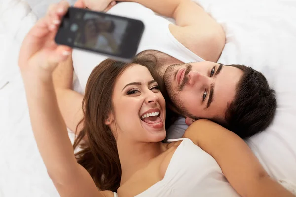 Casal tomando selfie na cama — Fotografia de Stock