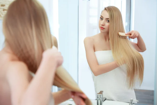Волосся. Красива блондинка чищення зубів її волосся. Засоби догляду за волоссям. Спа-салон краси М — стокове фото