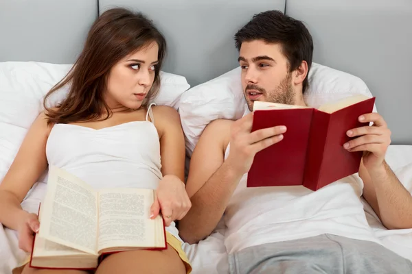 Pareja feliz sentada en la cama leyendo libros en casa en el dormitorio —  Fotos de Stock