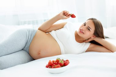 Pregnant Woman Eating Strawberry at home. Healthy Food Concept.