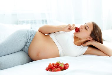 Pregnant Woman Eating Strawberry at home. Healthy Food Concept.