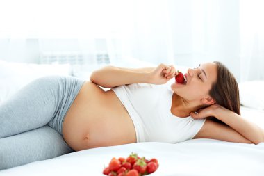 Pregnant Woman Eating Strawberry at home. Healthy Food Concept.