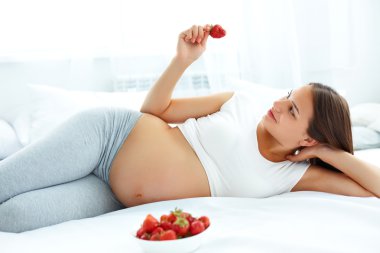 Pregnant Woman Eating Strawberry at home. Healthy Food Concept.