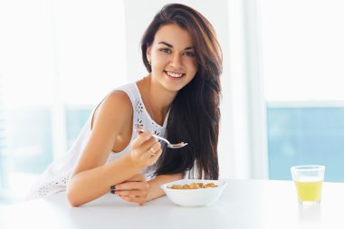 Woman eating cereal and smiling at the camera