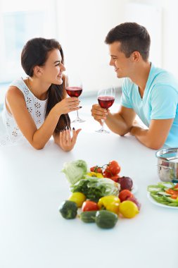 Couple enjoying wine while working in kitchen