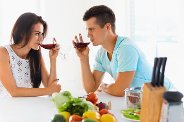 Couple looking at each other while drinking red wine in kitchen