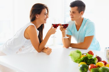 Wife and husband with wine and vegetables in kitchen