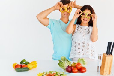 Couple with pepper slices smiling at the camera. Vegetables for