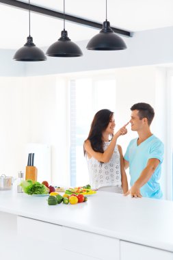 Couple preparing dinner.  Woman is touching man's nose