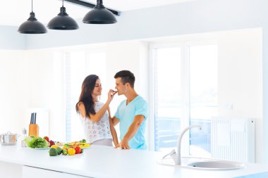 Woman feeding her man in their kitchen clipart