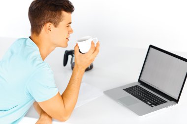Man having a cup of coffee while working on laptop