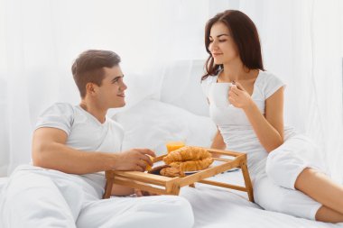 Çift yatakta kahvaltı yapıyor.