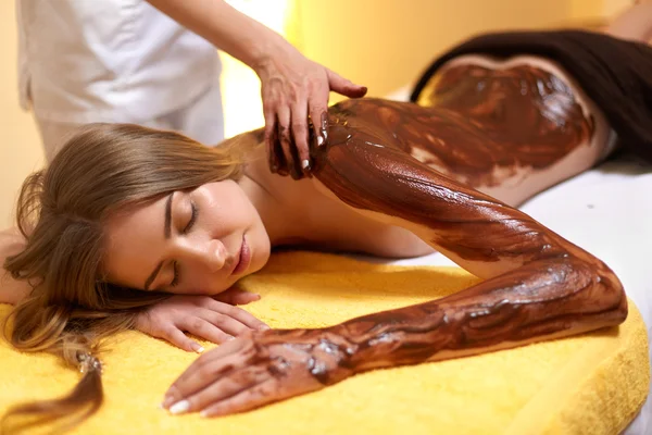 Mujer Spa. Joven mujer consigue chocolate máscara corporal en salón de belleza — Foto de Stock