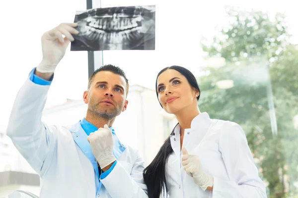 Dokter gigi dan asisten wanita sedang mendiskusikan gambar sinar X gigi. — Stok Foto