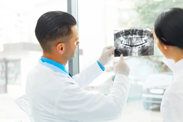 Dentysta i asystent kobiet dyskutują stomatologiczne X Ray obrazów — Zdjęcie stockowe