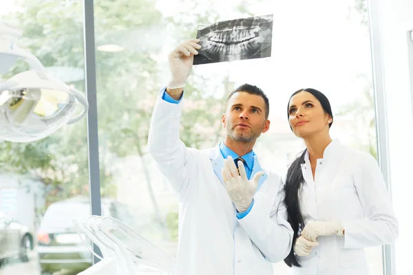 Zubař a asistent diskutujeme zubní rentgenový obraz — Stock fotografie