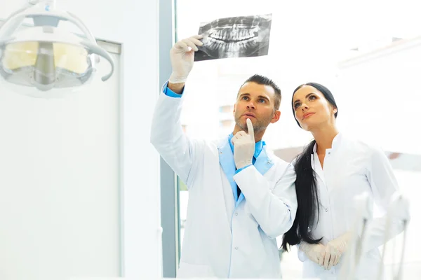 Dentysta i asystent kobiet dyskutują stomatologiczne X Ray obrazów — Zdjęcie stockowe