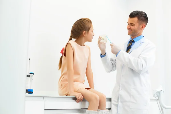 Dentist showing a girl how to brush her teeth. — Stock Photo, Image