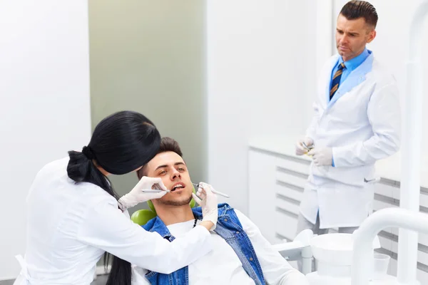 Dentysta z asystent bada zęby w fotelu Dentyści. — Zdjęcie stockowe