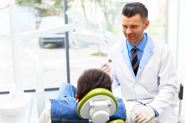 Dentysta i pacjent w gabinecie dentysty. Młody człowiek w Dental — Zdjęcie stockowe