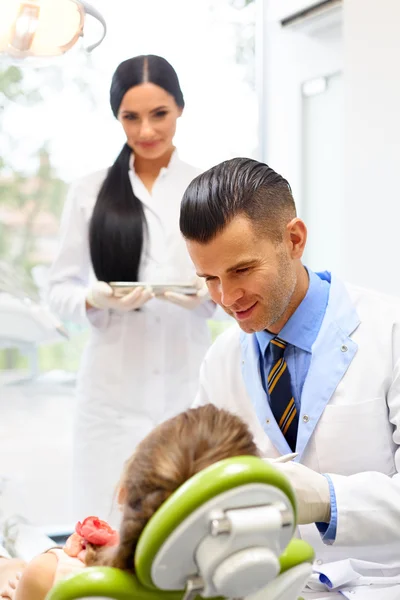 Dentista con assistente esaminando i denti delle bambine nel Denti — Foto Stock