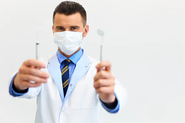 Dentista con una herramienta sobre un fondo blanco — Foto de Stock