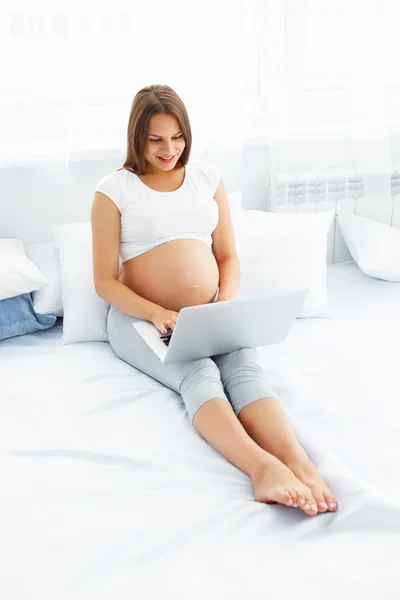 Pregnant woman with laptop. Beautiful pregnant woman working on — 图库照片