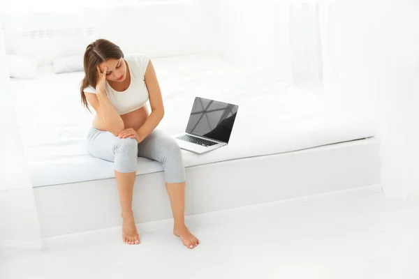 Depressed Pregnant Woman with a Laptop Computer While sitting on — Stockfoto