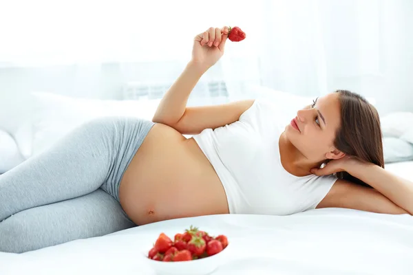 Pregnant Woman Eating Strawberry at home. Healthy Food Concept. — Stock fotografie