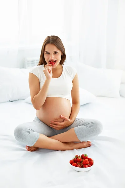 Donna incinta Mangiare fragole a casa. Concetto di cibo sano . — Foto Stock