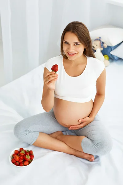 Donna incinta Mangiare fragole a casa. Concetto di cibo sano . — Foto Stock